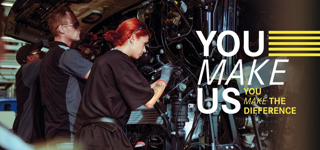 Young employees assemble parts on a truck in Daimler Truck Production - teamwork and commitment in a holiday job. Text in the picture: ‘You make us - You make the difference.’